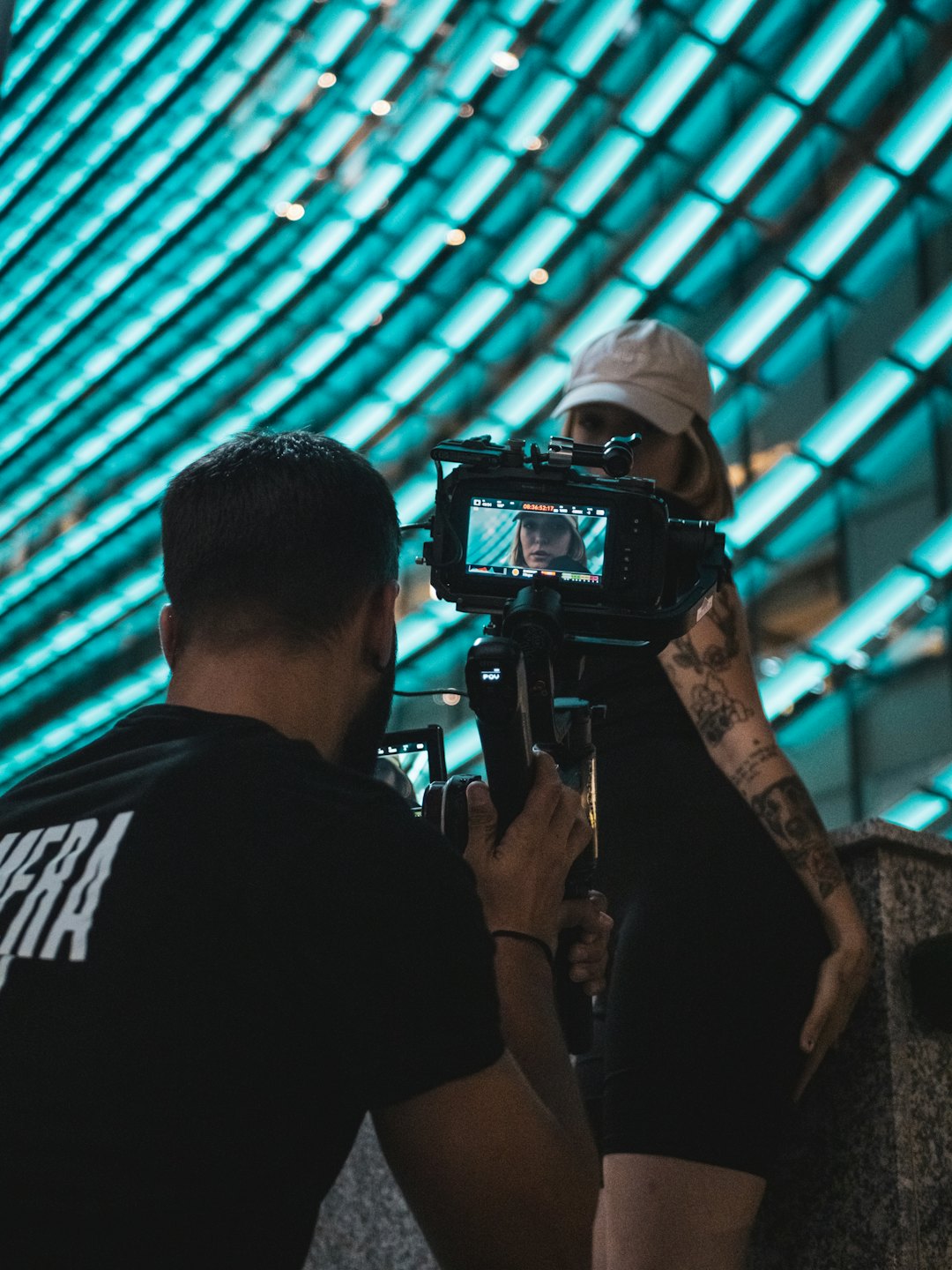Filmmaker recording a woman in front of a modern building.